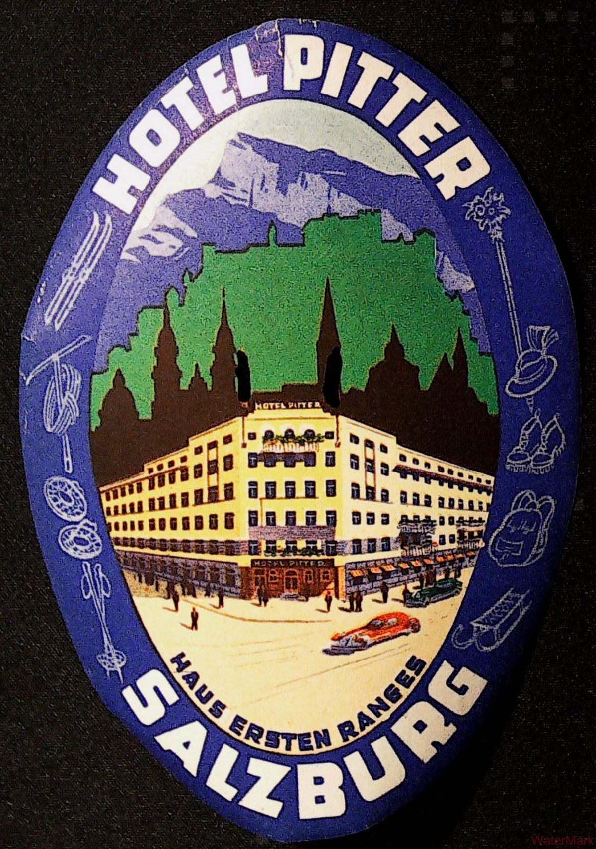 Large oval Hotel Pitter Salzburg luggage label with Alpine scenery, hotel illustration and sports equipment around a blue-purple border