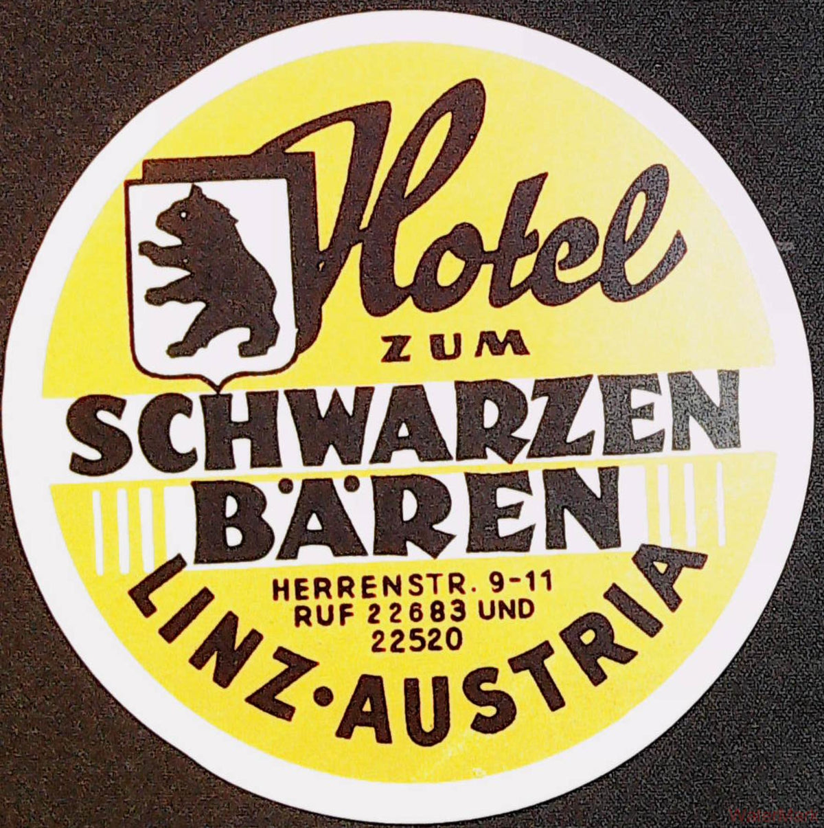Circular yellow Hotel zum Schwarzen Bären Linz Austria luggage label with black bear shield and white border